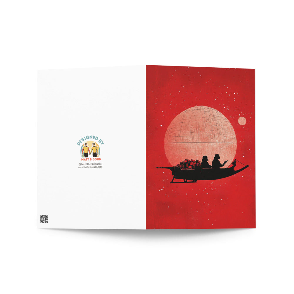 Close-up of the Star Wars Christmas card design highlighting the vibrant red background, the Death Star silhouette, and playful robots in a whimsical holiday setting.