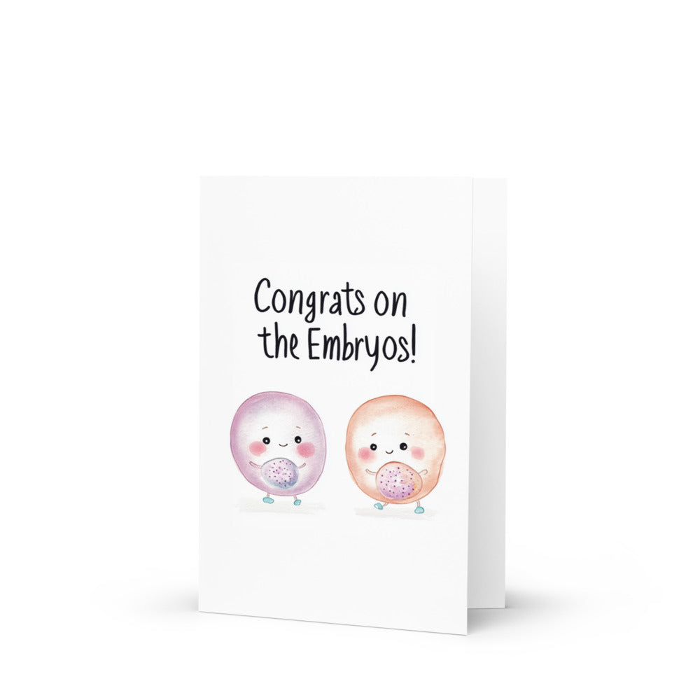 Cute cartoon-style embryos on a greeting card, celebrating new beginnings with a whimsical design featuring smiling faces and rosy cheeks against a clean white background.