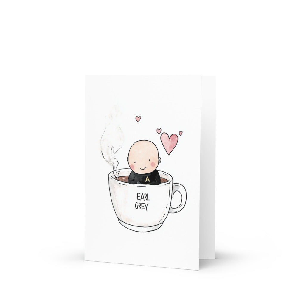 Charming Captain Picard-themed greeting card featuring a cute cartoon drawing of a character resembling Picard sitting in a giant white mug of Earl Grey tea, perfect for Star Trek fans and tea lovers.