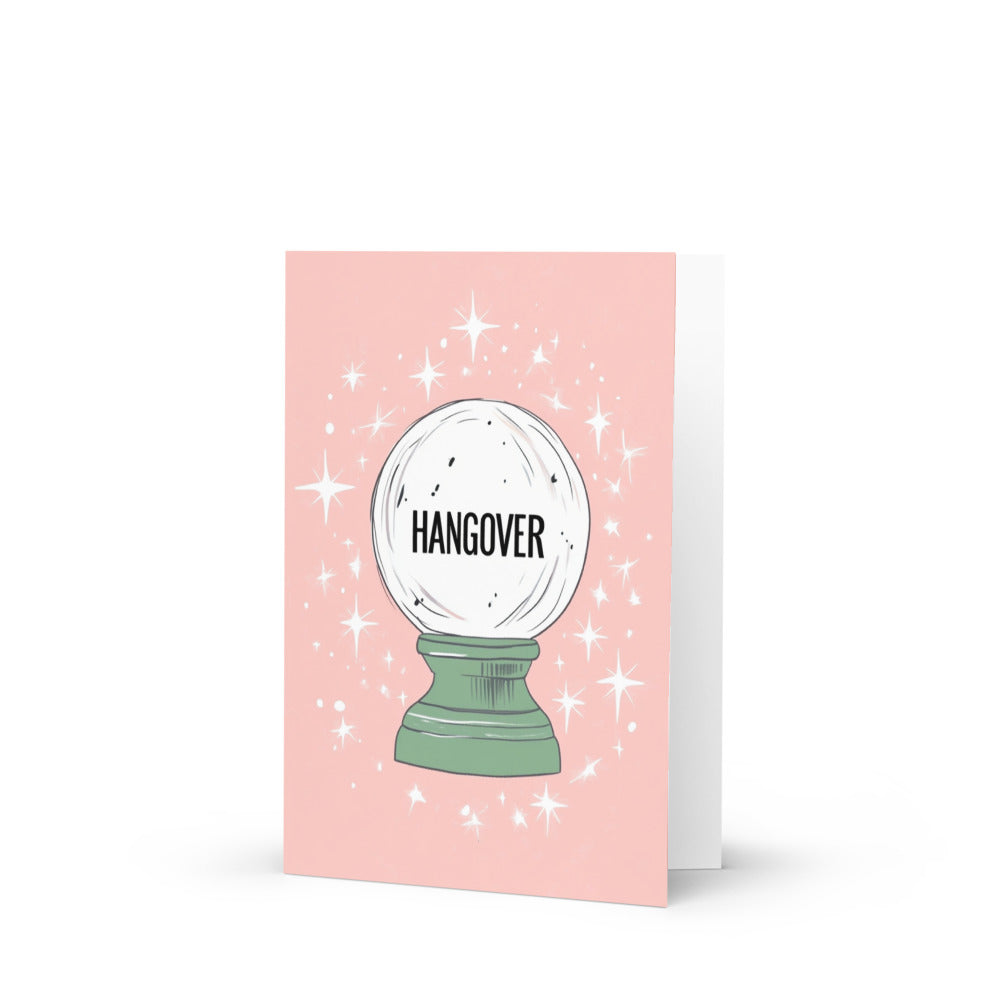 A whimsical HANGOVER greeting card featuring a playful crystal ball design against a soft pastel pink background with magical stars, perfect for post-party humor.